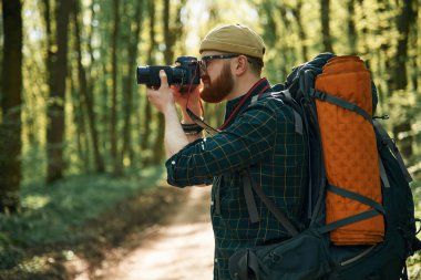 Kameralı fotoğrafçı. Sakallı adam gündüz vakti ormandadır..