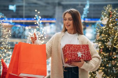 Kırmızı alışveriş torbaları. Yeni yıl hediyeleri. Kadın Noel ağacının yanında..