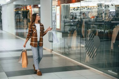 Koridorda, camın yanında. Kadın süpermarkette alışveriş yapıyor..