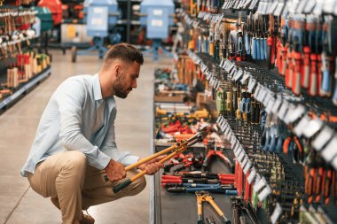 Turuncu renkli tel kesici, el ele tutuşuyor. Adam hırdavatçıda..