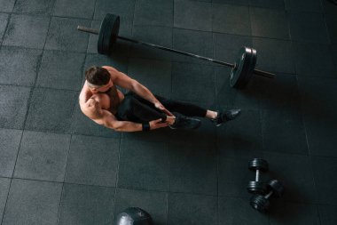 Yukarıdan bak. Güçlü kaslı adam spor salonunda çalışıyor..