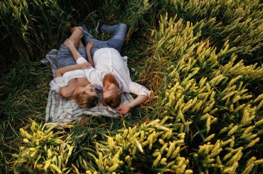 Dinleniyor, uzanıyor, yukarıdan bakıyor. Güzel bir çift yeşil tarlada birlikte..