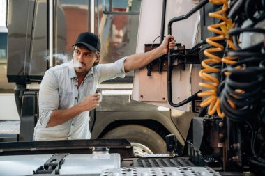 Kablolarla uğraşmak, kurulum, tamir. Kamyon şoförü açık havada nakliye aracının yanında..