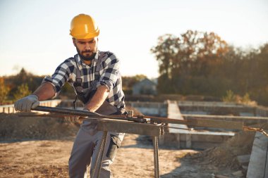 Metal çubukla çalışmak. Gündüz vakti şantiyede bir adam var..