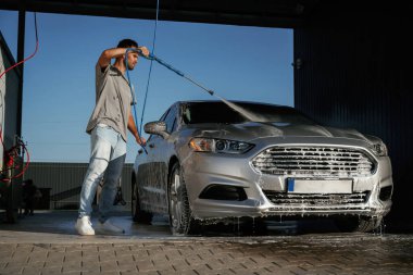 Etrafta dolaşmak ve otomobili yıkamak. Adam dışarıda arabasıyla bekliyor..