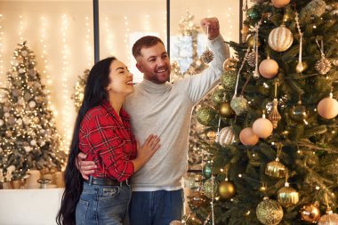 Noel ağacı süsleme süreci. Çift içeride yeni yılı kutluyor..