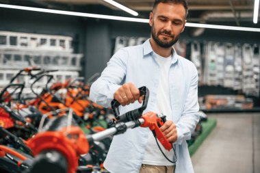 Çim biçme makinesi ellerinde. Adam hırdavatçıda..