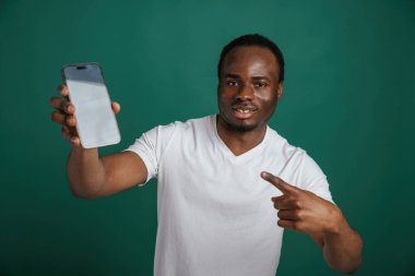Mesaj için beyaz boş alanı olan akıllı telefon. Afrikalı Amerikalı adam stüdyoda yeşil arka plana karşı duruyor..