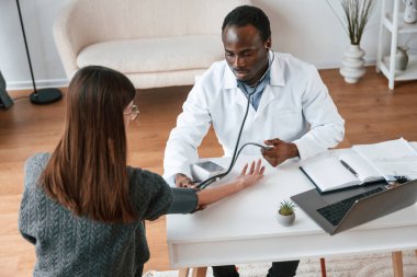 Müşteri hizmetleri. Bir doktor genç bir kadının kan basıncını ölçer..