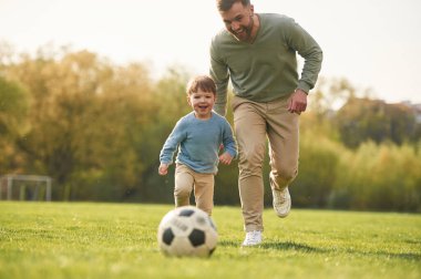 Futbol oynamayı öğreniyorum. Mutlu baba ve oğul yazın sahada eğleniyorlar..