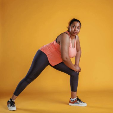 Fitness yapıyorum. Afrikalı Amerikalı kadın sarı arka planda stüdyoda..