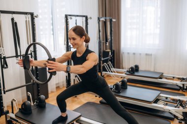 Ayakta duruyorum, spor yapıyorum. Genç bayan antrenman malzemeleriyle spor salonunda..