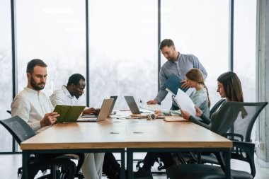 Masada bir sürü dizüstü bilgisayar var. Ofis çalışanlarından oluşan ekip içeride bir arada..