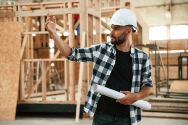 Emirleri el hareketleriyle veriyor. Ahşap depoda sanayi işçisi..