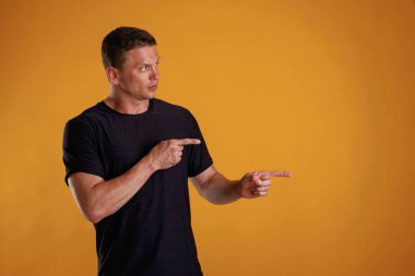 Yan tarafı gösteriyor, işaret ediyor. Adam stüdyoda arka plana karşı..