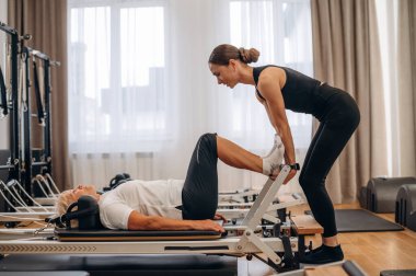 Bacak egzersizi. Kadın eğitmen yaşlı kadına yardım ediyor..