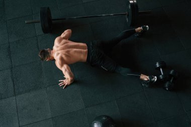 Yukarıdan bak. Güçlü kaslı adam spor salonunda çalışıyor..