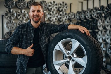 Gülümseme, pozitif yüz ifadesi, el hareketi. Tekerlekleri ve tekerlekleri olan tamirci var..