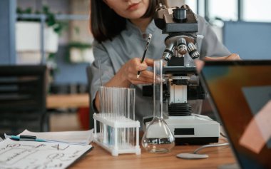 Mikroskopla. Paltolu kadın doktor içeride..