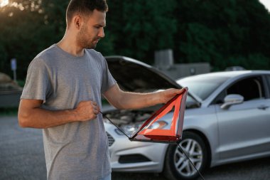 Kırmızı ışığı var, bozuk otomobil var. Adam dışarıda arabasıyla bekliyor..