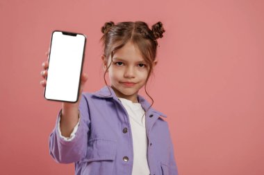 Beyaz fotokopi alanı olan akıllı telefon. Şirin küçük kız pembe arka plana karşı..