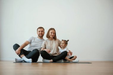 Neşeli insanlar. Anne, baba ve kızı evde yoga yapıyor..