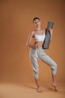 Dört gözle bekliyorum, elimde bir şişe su ve hasırla. Güzel fitness kadını stüdyoda..