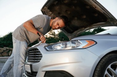 Kaput açıldı, tamir ediliyor. Adam dışarıda arabasıyla bekliyor..