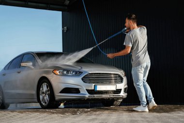 Otomobil yıkama, adam dışarıda arabasıyla bekliyor..