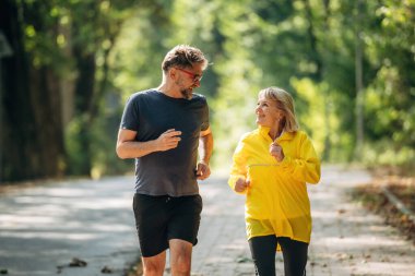 Parlak güneş ışığı, koşu, koşu, spor. Doğada üst düzey çiftler birlikte..