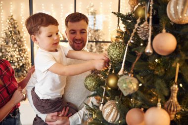 Kutlama havası, dekorasyon ağacı. Mutlu bir aile yeni yılı evde kutluyor..