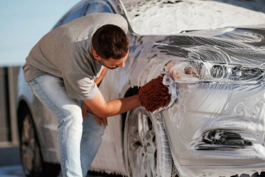 Otomobili yıkama işlemi. Adam dışarıda arabasıyla bekliyor..