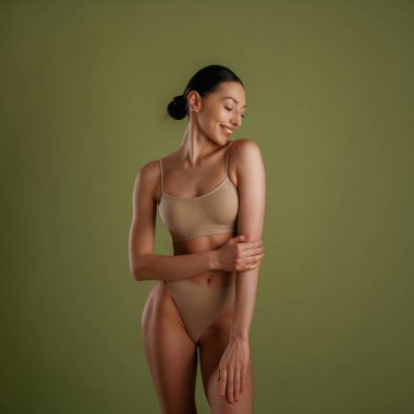 Gülümseyen, neşeli yüz ifadesi. İnce vücutlu kadın arka planda poz veriyor..