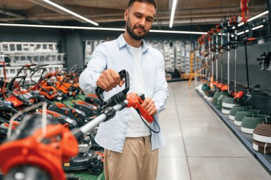 Çim biçme makinesi ellerinde. Adam hırdavatçıda..