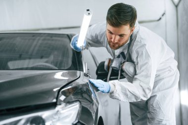 Otomobilin ön tarafında. Garaj çalışanı arabanın aydınlatma ve kontrol yüzeyini tutuyor..