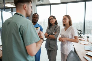 Büyük panoramik pencerelere karşı. Bir grup doktor içeride birlikteler..