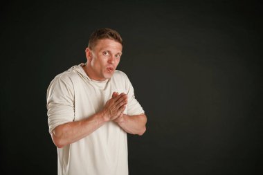 Kirli düşünceler, ellerini ovuşturuyor. Adam stüdyoda arka plana karşı..