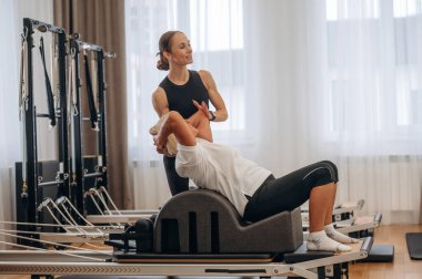 Aktif eğitim. Kadın eğitmen yaşlı kadının egzersiz yapmasına yardım ediyor..