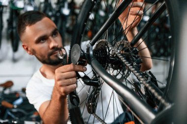 Tekerlek ve fren sistemini kontrol ediyorum. Bisiklet dükkanında tamirci, mağazada çalışıyor..