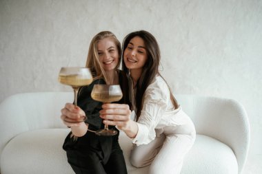 Siyah beyaz giysiler içinde, içkiyle, kutlama yaparak. İki mutlu genç bayan en iyi arkadaş içeride..