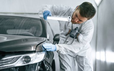 Ön manzara. Garaj çalışanı arabanın aydınlatma ve kontrol yüzeyini tutuyor..