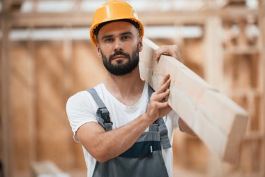 Tahtayı taşıyorum. Ahşap depoda sanayi işçisi..