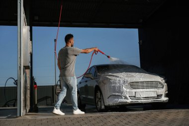 Yüksek basınç, otomobili yıkamak. Adam dışarıda arabasıyla bekliyor..