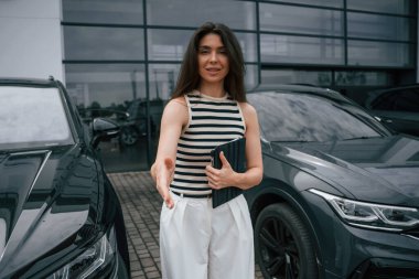 Dijital tablet hazır. Çekici genç bayan dışarıda, yepyeni arabasının yanında..