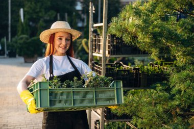 Genç kızıl saçlı kadın bahçeyle ilgileniyor..