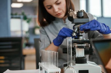 Mikroskopla. Paltolu kadın doktor içeride..