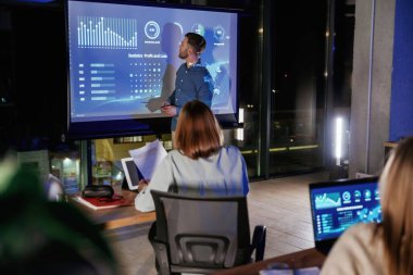 Şirketin büyümesine yardım etmek. Erkek işletme eğitmeni projektöre karşı, insanlara öğretiyor..