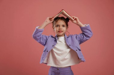 Not defteri ya da kitap, eğitim anlayışı. Şirin küçük kız pembe arka plana karşı..