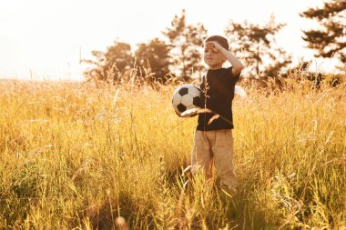 Futbol topunu tutuyorum. Küçük çocuk yazın dışarıda eğleniyor..