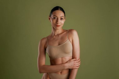 Yeşil arka plan. İnce vücutlu kadın içeride poz veriyor..